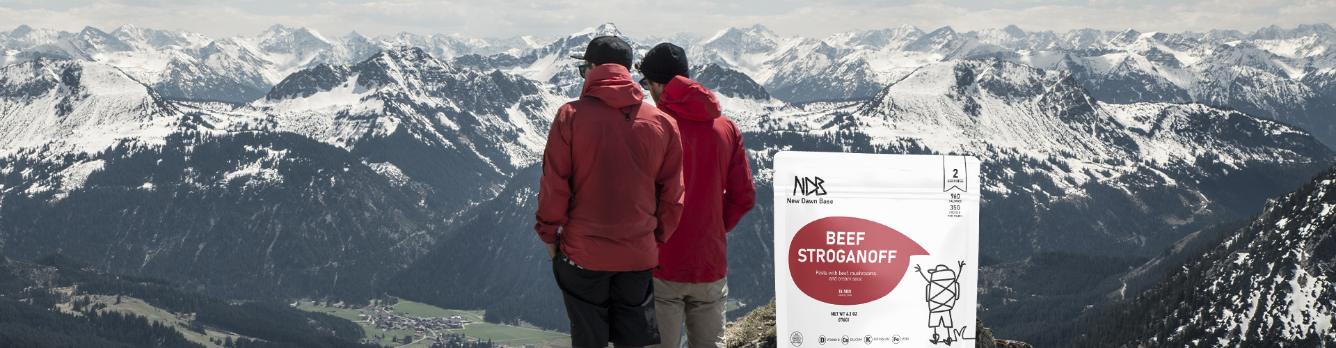 Hikers overlooking snowy mountain peaks with New Dawn Base meal pouch